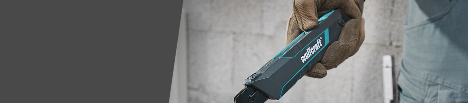 Hand holding a Wurth tool against a concrete wall background